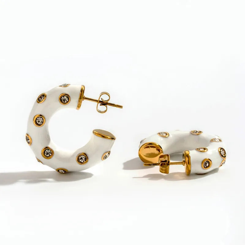 Pair of white hoop earrings with gold accents and small crystals on a white background